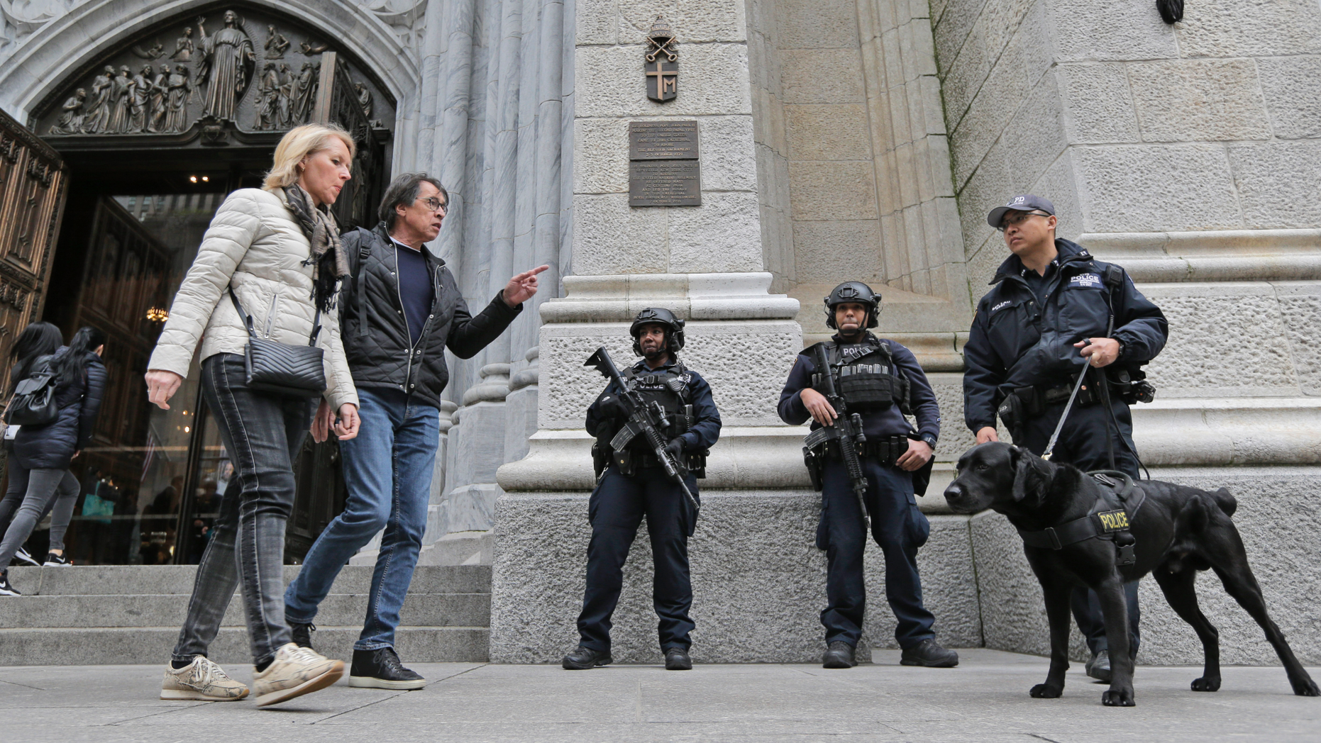Tourists Pass Policemen Standing in Front of St. Patrick's Cathedral in New York on Thursday, April 18, 2019. A man from New Jersey was arrested when he entered the cathedral and two jerrycans, lighter liquid and butane lighters, the New York Police Department said just days after the flames that devastated Notre Dame Cathedral in Paris. (AP Photo / Seth Wenig)
